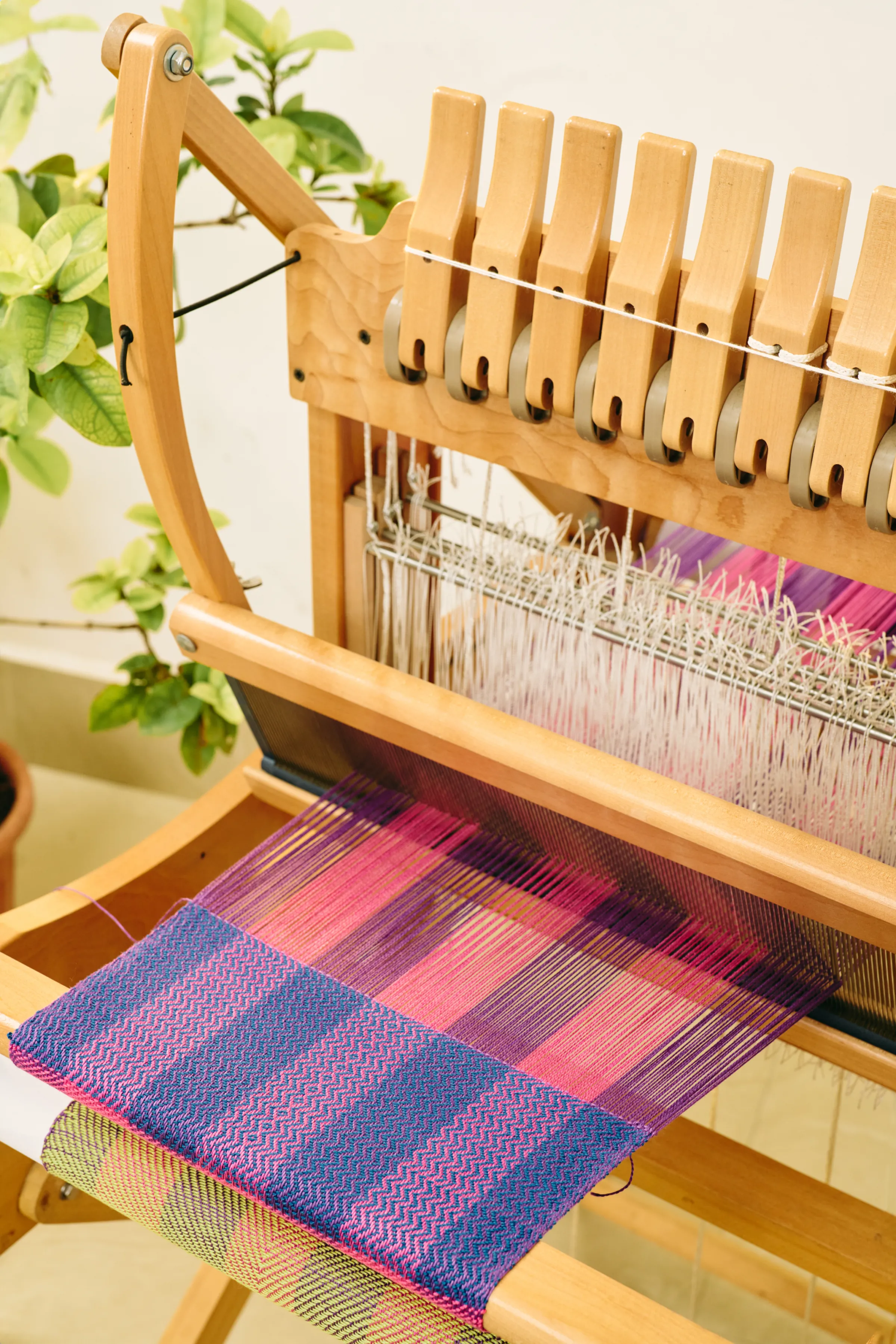 A floor loom warped in pinks and purples