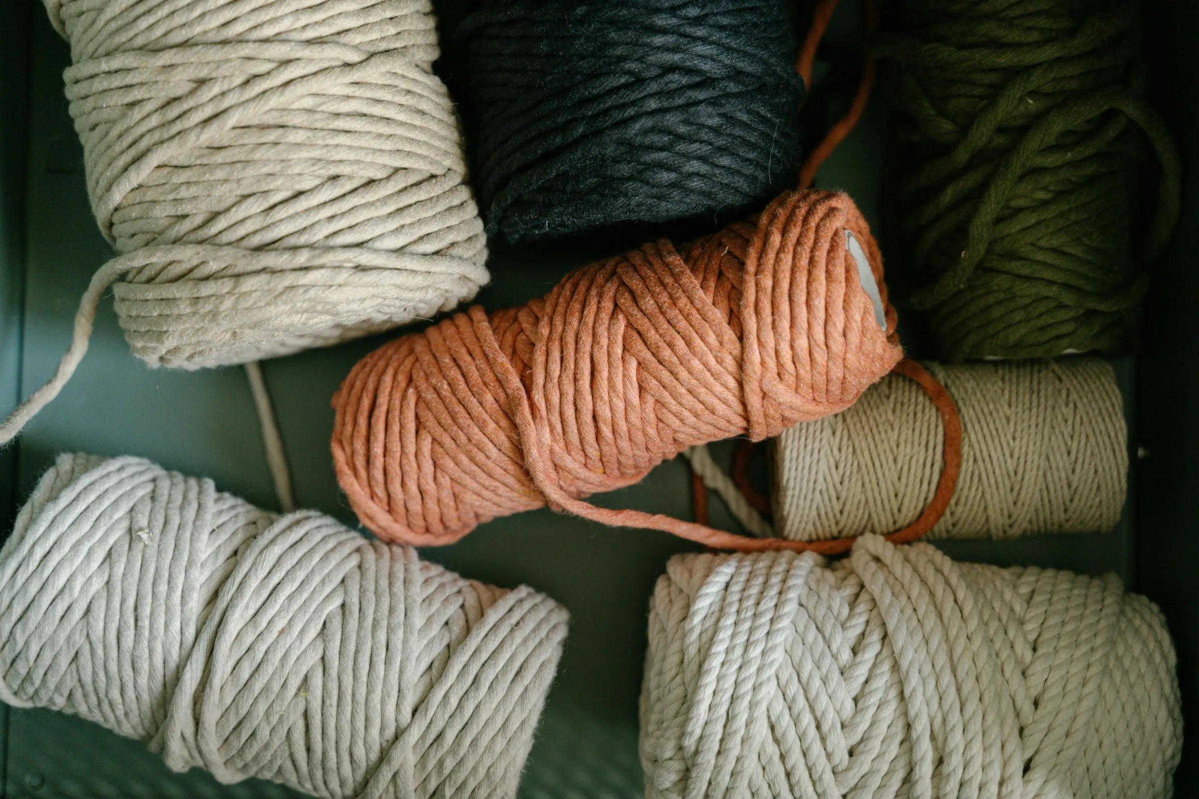 Hanks of thick cotton cord yarn in rust, natural, grey and dark green