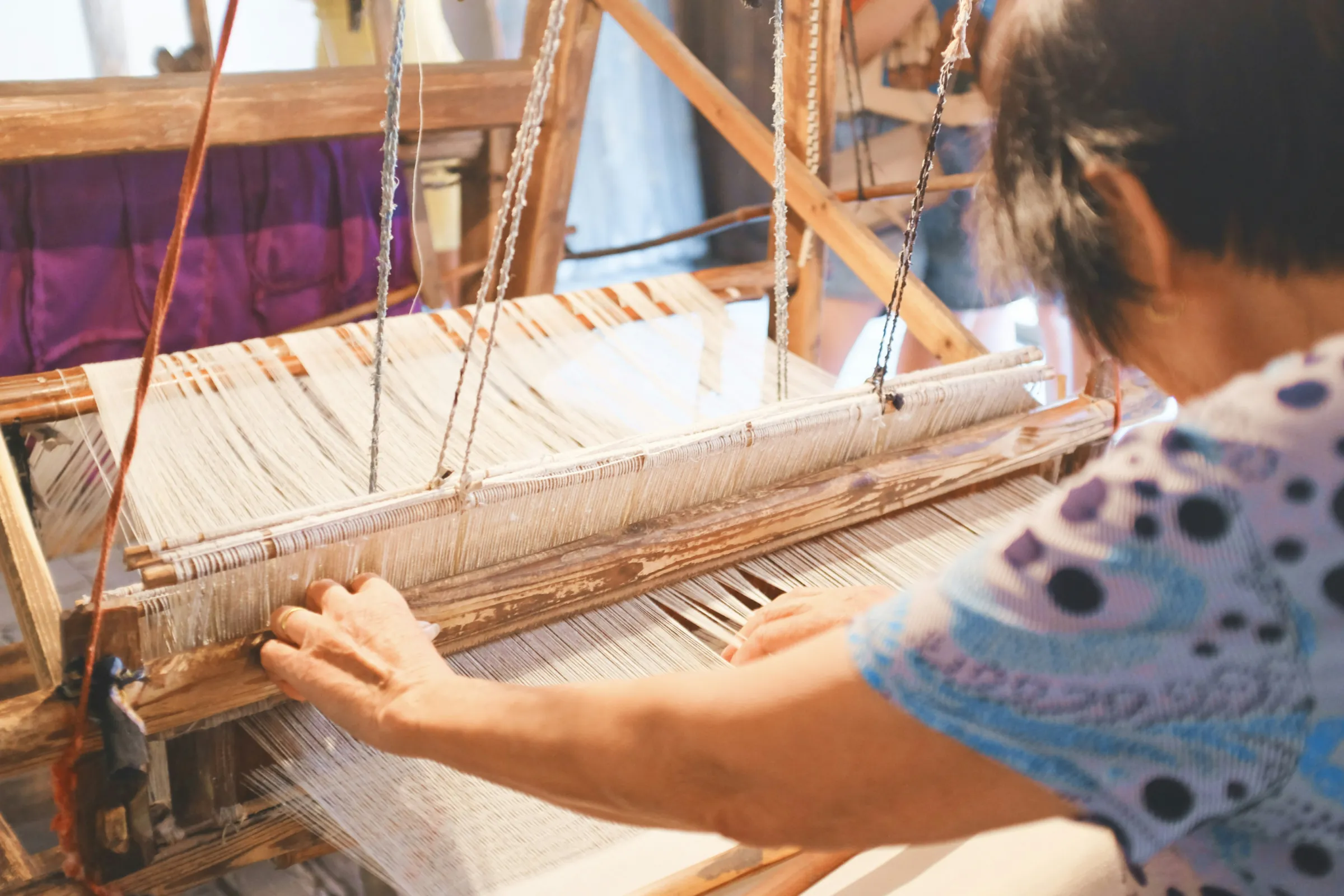 Hands weaving on a floor loom
