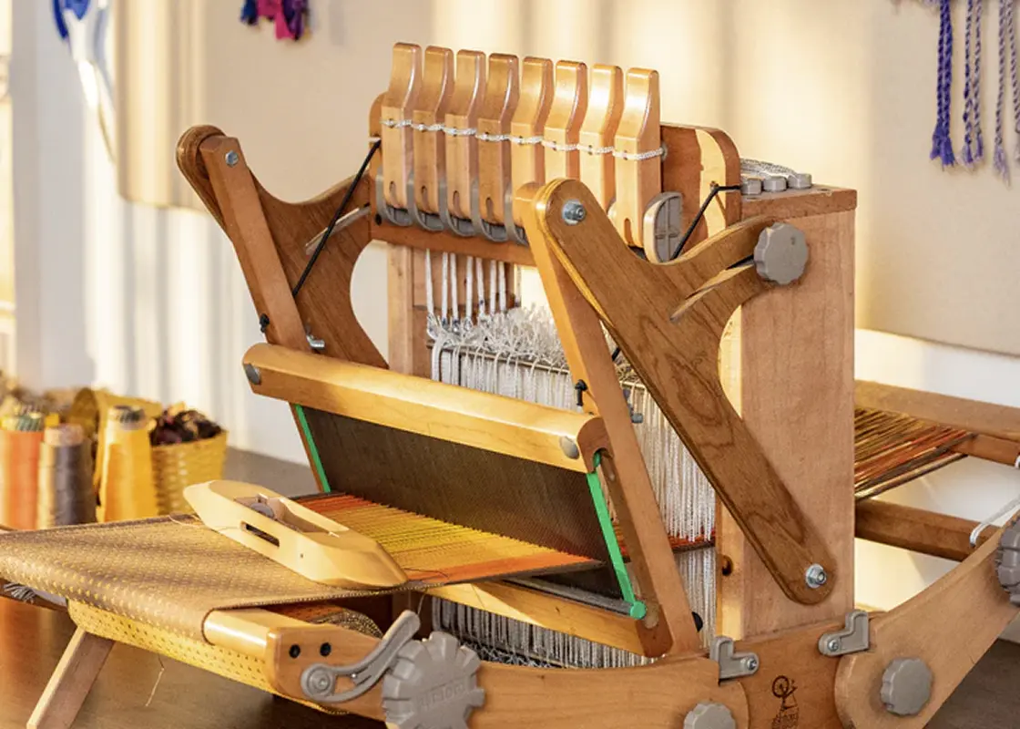 A wooden multi-shaft table loom with its shafts raised