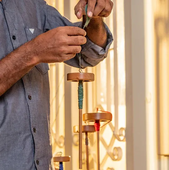 A spinner winding green yarn onto a drop spindle
