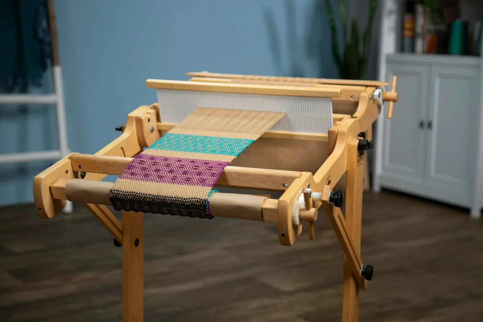 A rigid heddle loom with a teal and purple pick-up pattern