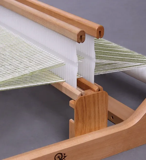 Close-up of a wooden table loom with a pale green warp