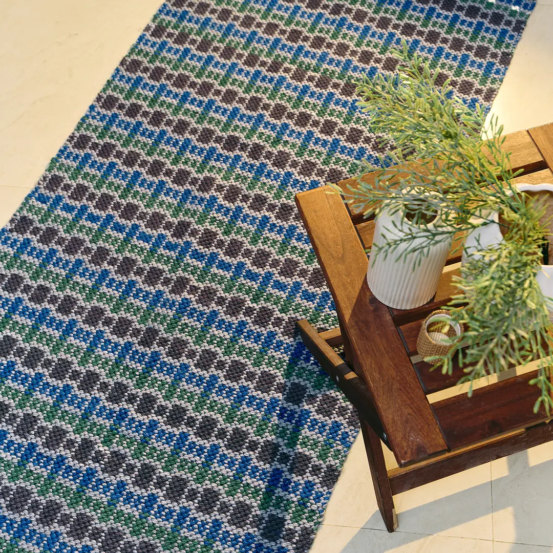 A blue and green handwoven runner draped over a small wooden stool